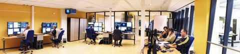 De operationsvloer van het datacenter: operators achter werkplekken met meerdere schermen vol monitoringoverzichten.