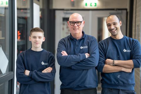 Drie collega's van een leerwerkorganisatie naast elkaar in de werkplaats.